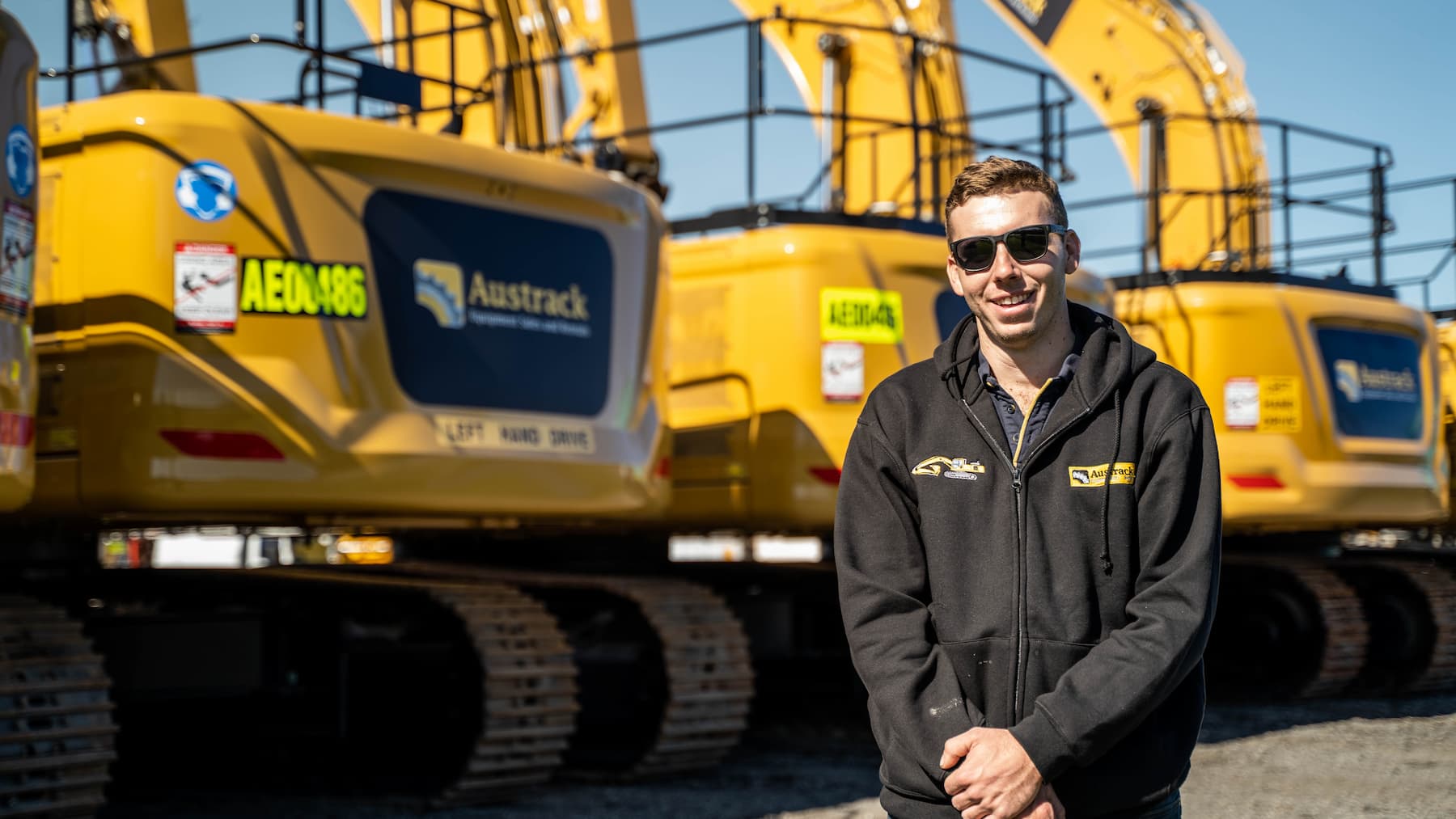 Dylan Gamble from Austrack standing in front of earthmoving equipment