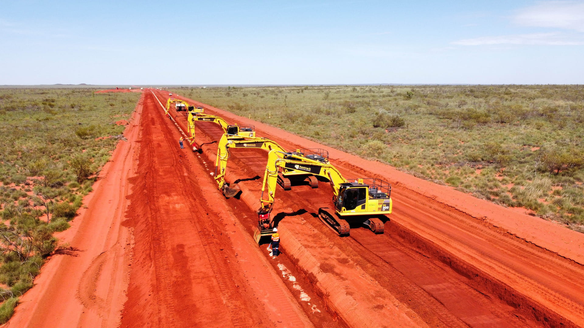 Multiple diggers preparing a trench and pipeline in outback australia